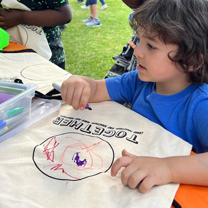Kid coloring a backpack that says Together