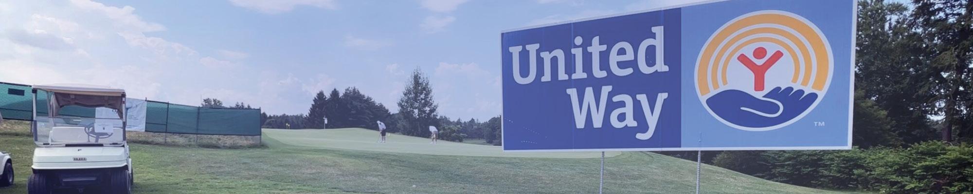 United Way lawn sign on the golf course with golfers in the background 
