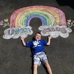 Boy laying under 5.18 Day chalk rainbow