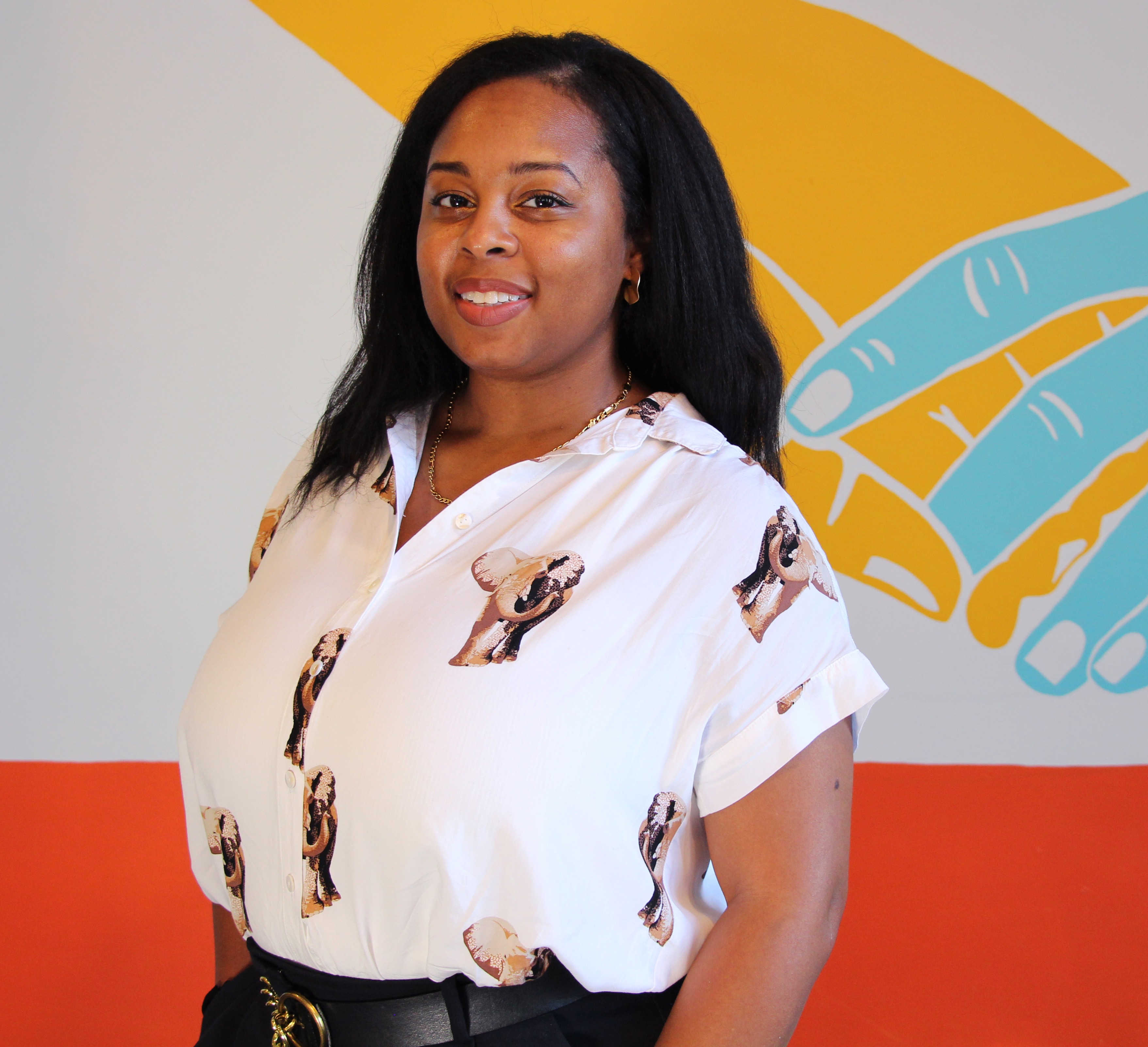 Loni Lee it white shirt with elephants on it against a colorful wall