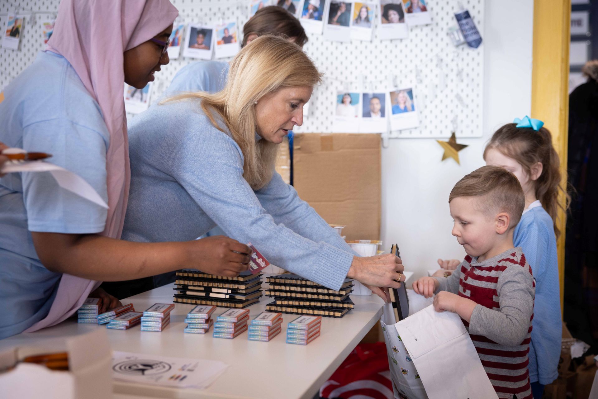 Volunteer helping a little boy put a book in his bag