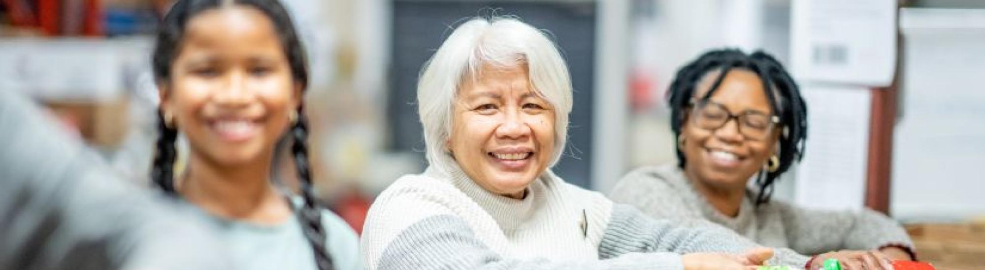 Three women smiling while sorting products in boxes