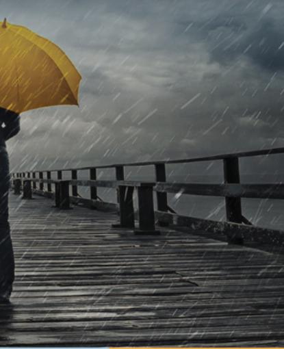 person walking on the boardwalk in the rain with yellow umbrella