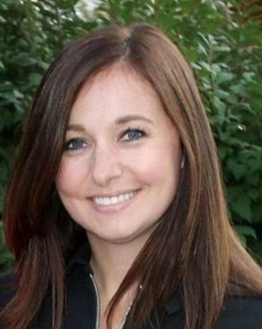 Brandi smiling, standing in front of bush