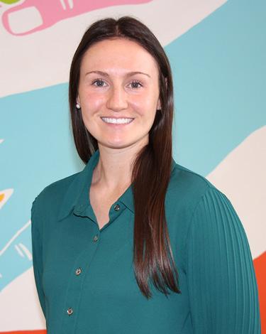 Allison in turquoise shirt smiling against colorful wall
